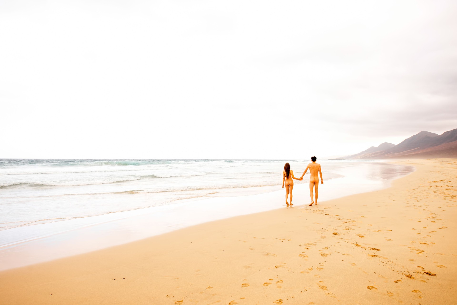 Naked couple walking on the beach